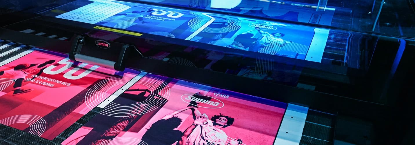 Large format printer producing vibrant banners with sports images and circular patterns in blue and pink hues.