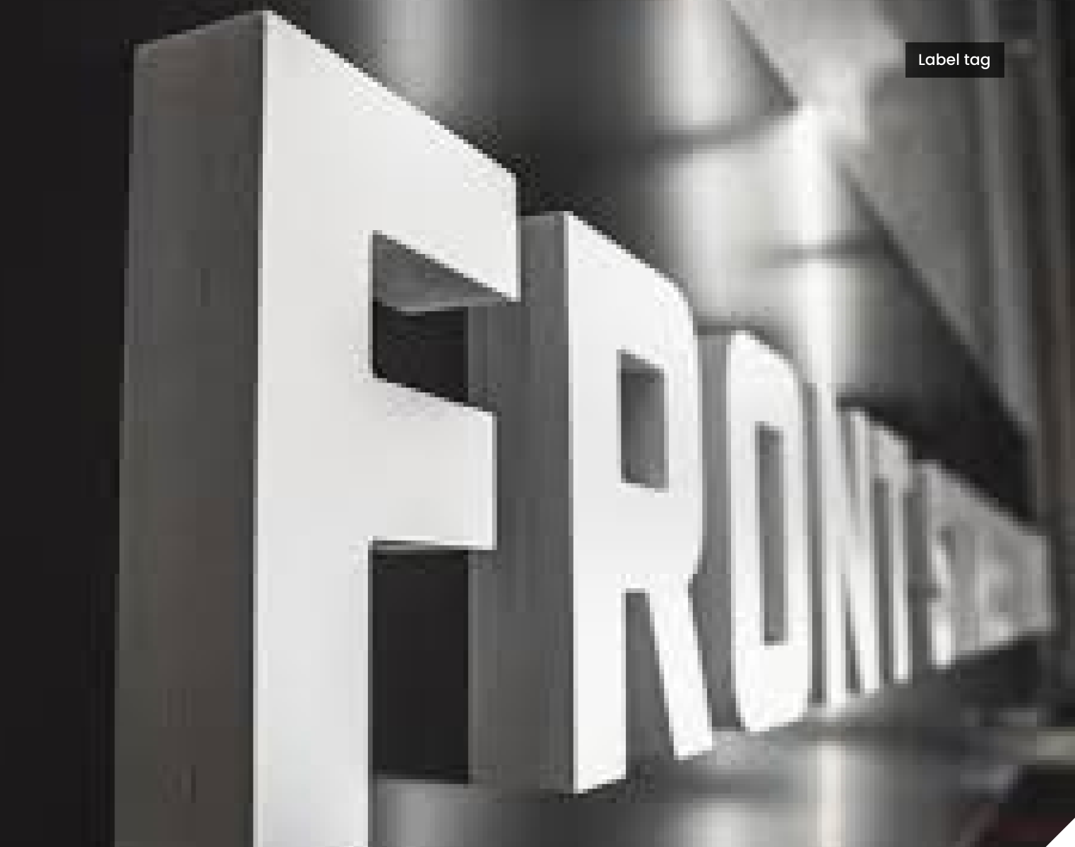 Close-up of large, white 3D letters spelling "FRONT" on a dark background, with lighting creating shadow contrasts.