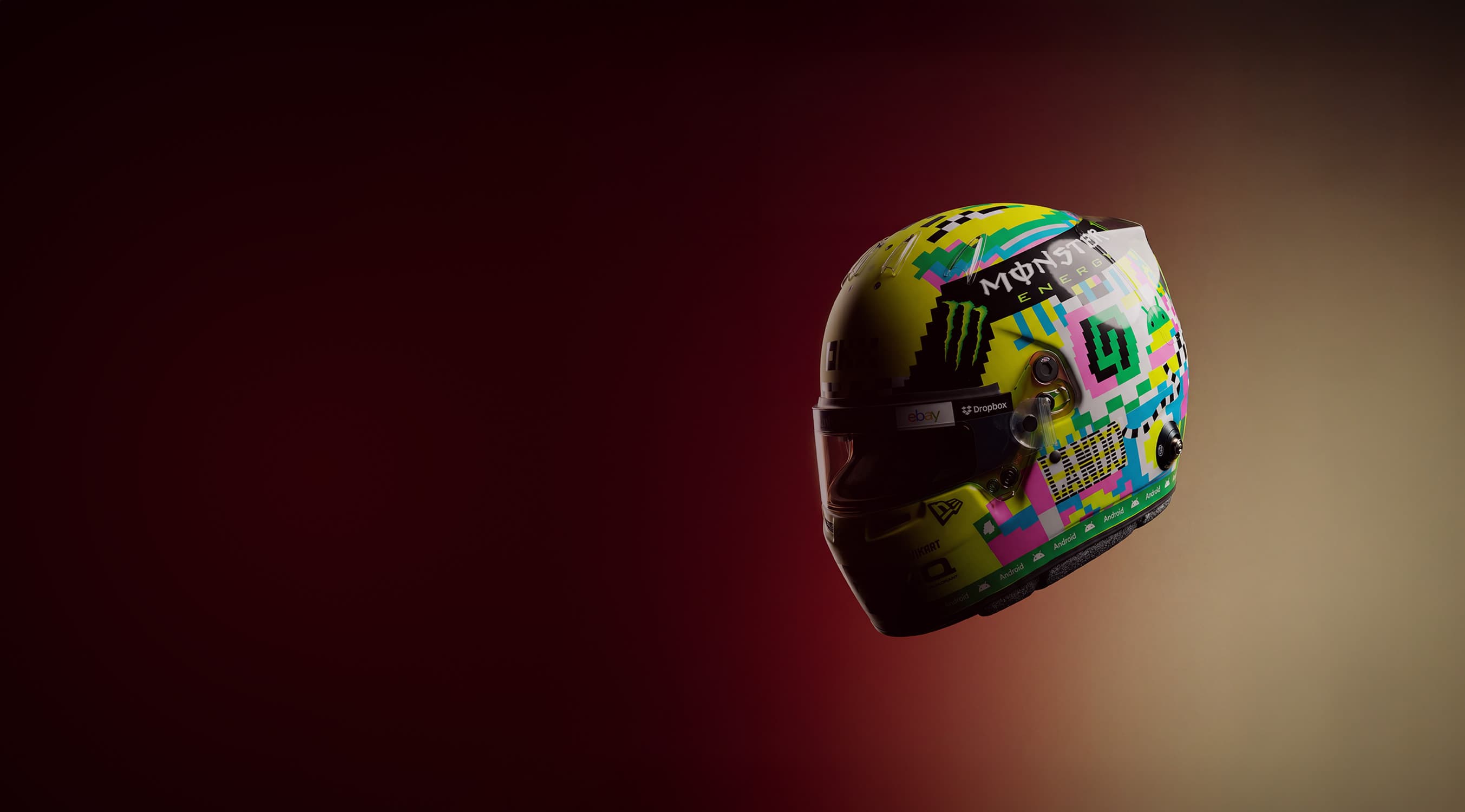 Colorful racing helmet with dynamic patterns and sponsor logos, set against a gradient maroon background.