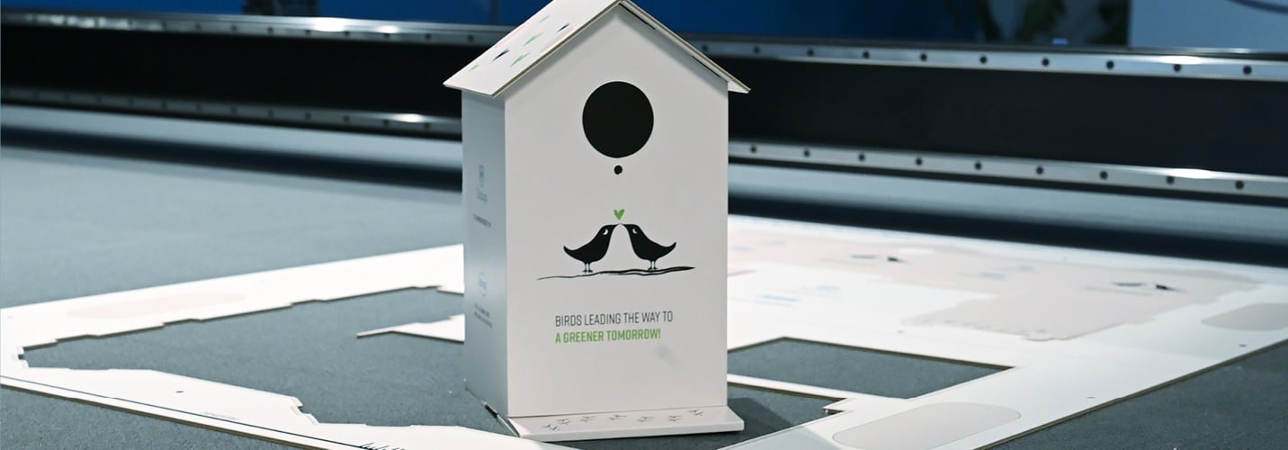 A birdhouse crafted from Oppboga board rests on a Summa flatbed cutting table, on which it was precisely cut.